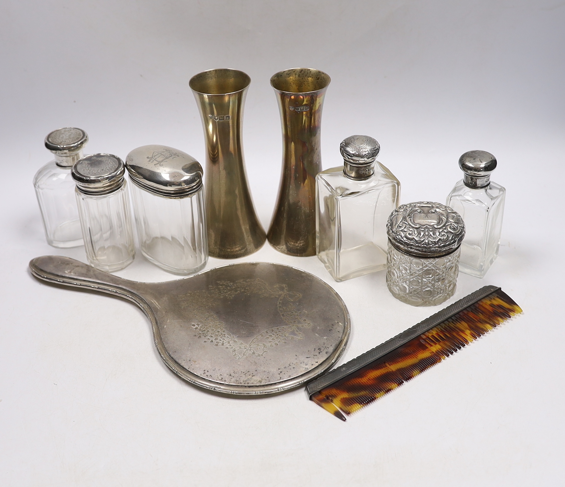 A pair of Edwardian silver waisted spill vase, London, 1907, 15cm, six silver mounted glass toilet jars, a silver mounted hand mirror and comb.